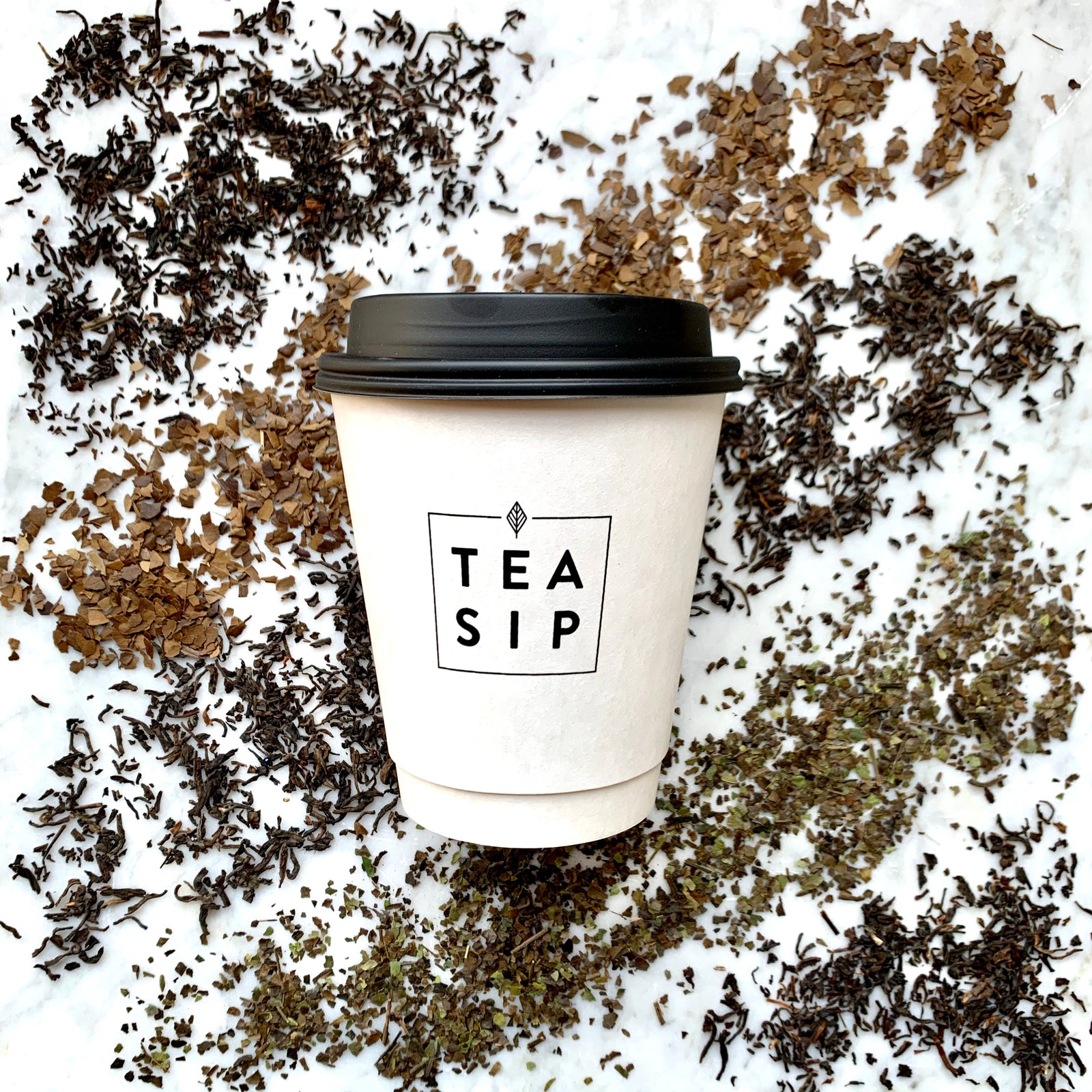 Tea sip cup surrounded by tea leaves