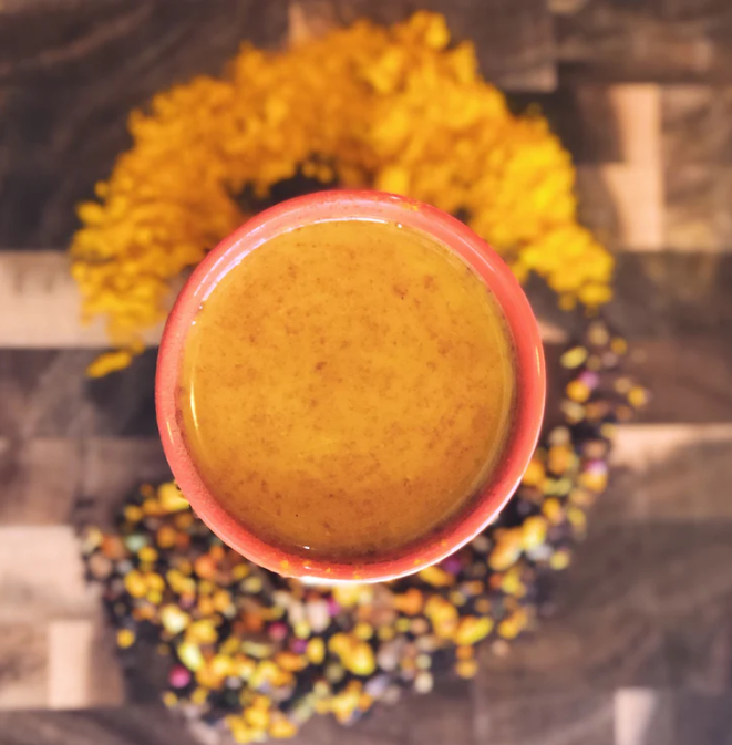 Golden Milk Latte top down shot surrounded by turmeric tease and turmeric powder.